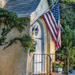 a photograph of the outside of house with an American flag hanging near the door