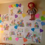 A photograph of a wall with many colorful and handdrawn drawings with hearts surrounding them.