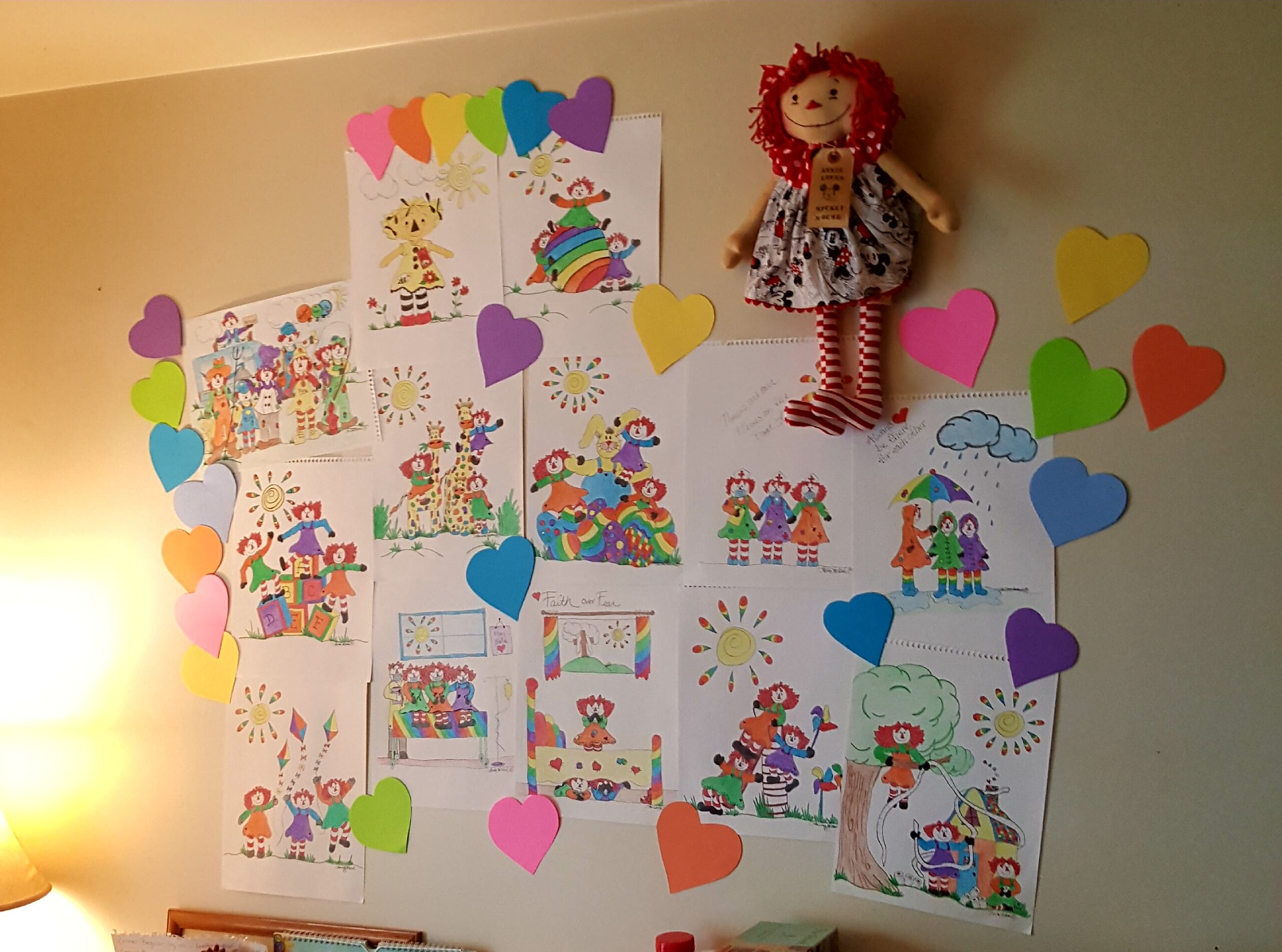 A photograph of a wall with many colorful and handdrawn drawings with hearts surrounding them.