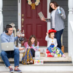 Photo showcasing a family working on the steps of there porch. Father and mother are on their laptops while children are playing with toys